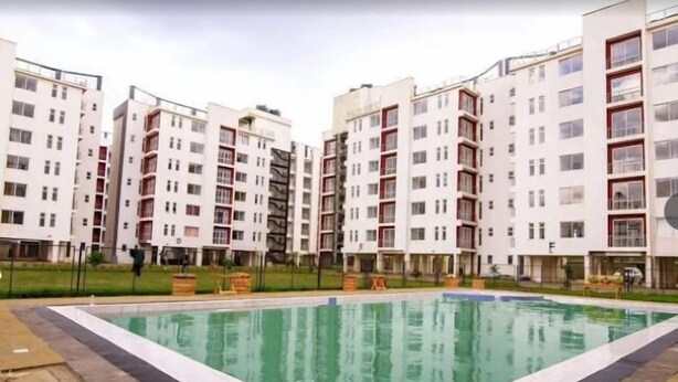 Ein moderner Apartmentkomplex mit einem zentral gelegenen Schwimmbad, umgeben von mehrstöckigen Gebäuden mit Balkonen.