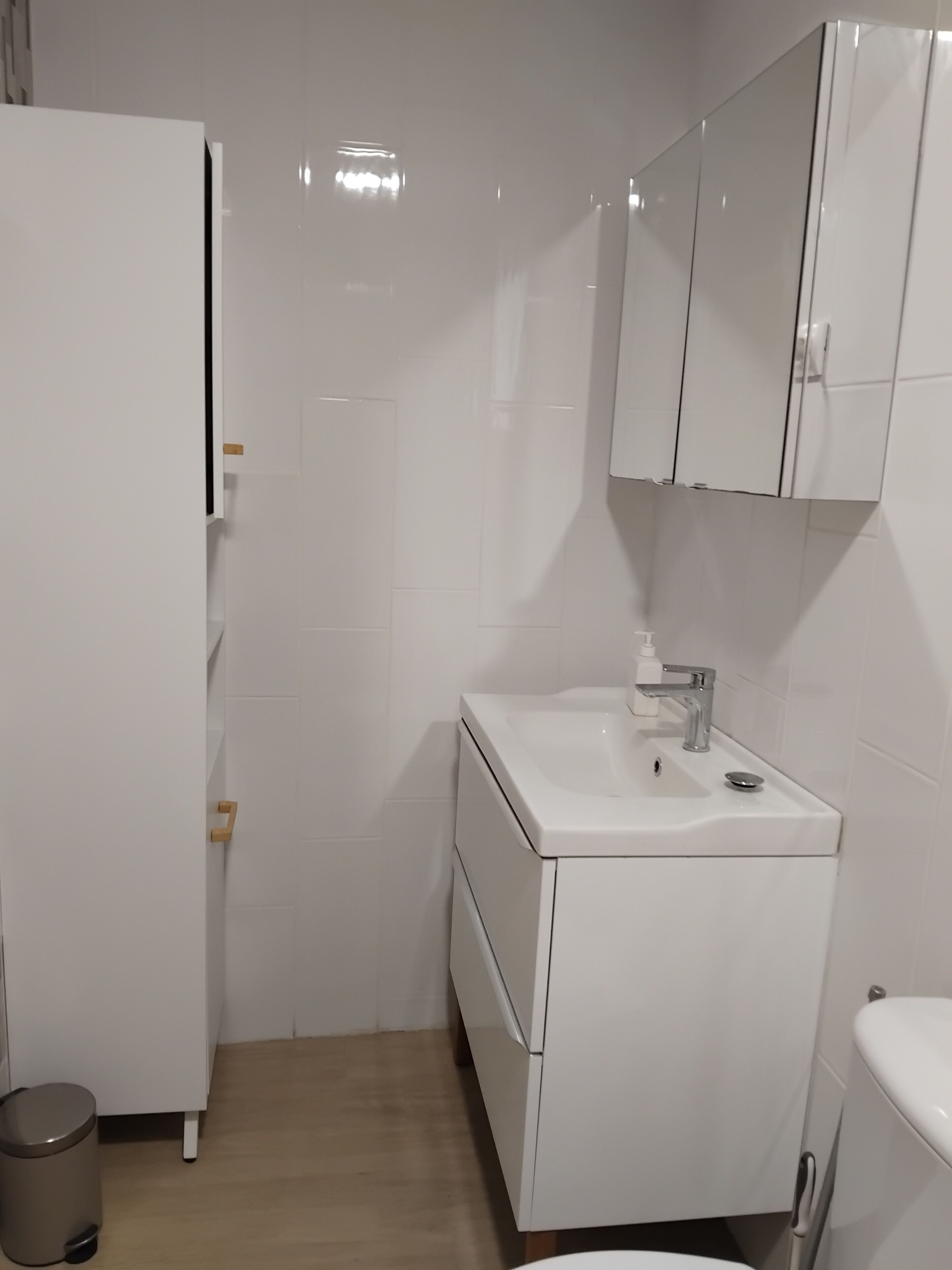 Ein kleines, modernes Badezimmer mit weißen Sanitärobjekten, einem Waschbecken, einem Spiegel und einer Toilette.