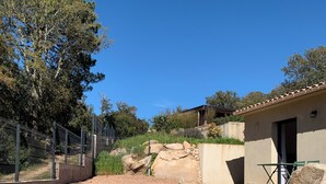 A fenced outdoor area with a building, large rocks, and trees. - Mini Villa, 15mn from Porto Vecchio (Sotta)