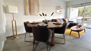 A modern dining area with a round table, chairs, and a sofa in the background. - Blue Pearl A102 by Avecoeur (Nice)