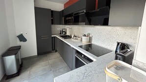 A modern kitchen with dark cabinets, a white countertop, and a marble backsplash. - Blue Pearl A102 by Avecoeur (Nice)