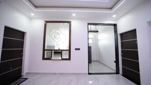 Un pasillo moderno con un muro espejado, dos puertas e iluminación empotrada en el techo.