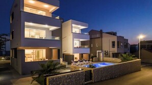 A modern multi-story residential building with a swimming pool and outdoor seating area.