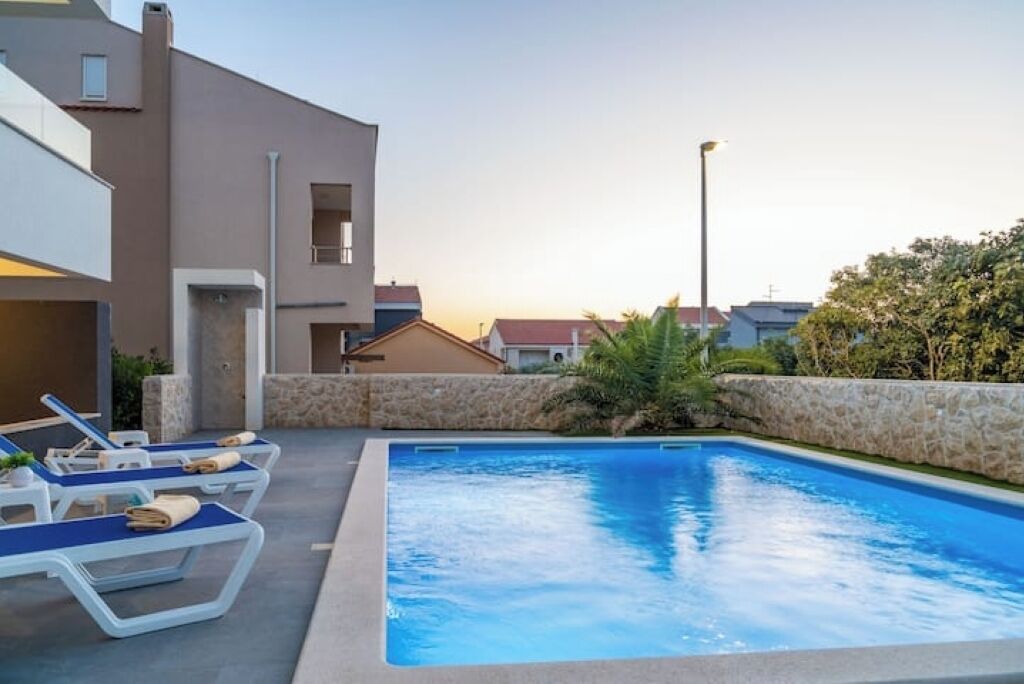 A swimming pool with lounge chairs and a stone wall.