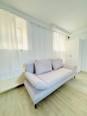 A minimalist room with a light-colored sofa, white curtains, and a white wardrobe. - Comfortable 2BR Apt for 7 Guests (Vienna)