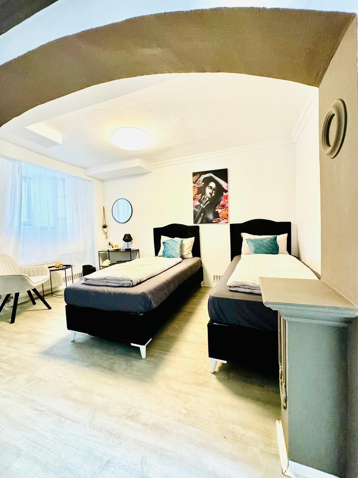 A modern bedroom with two beds, a desk, and a chair.