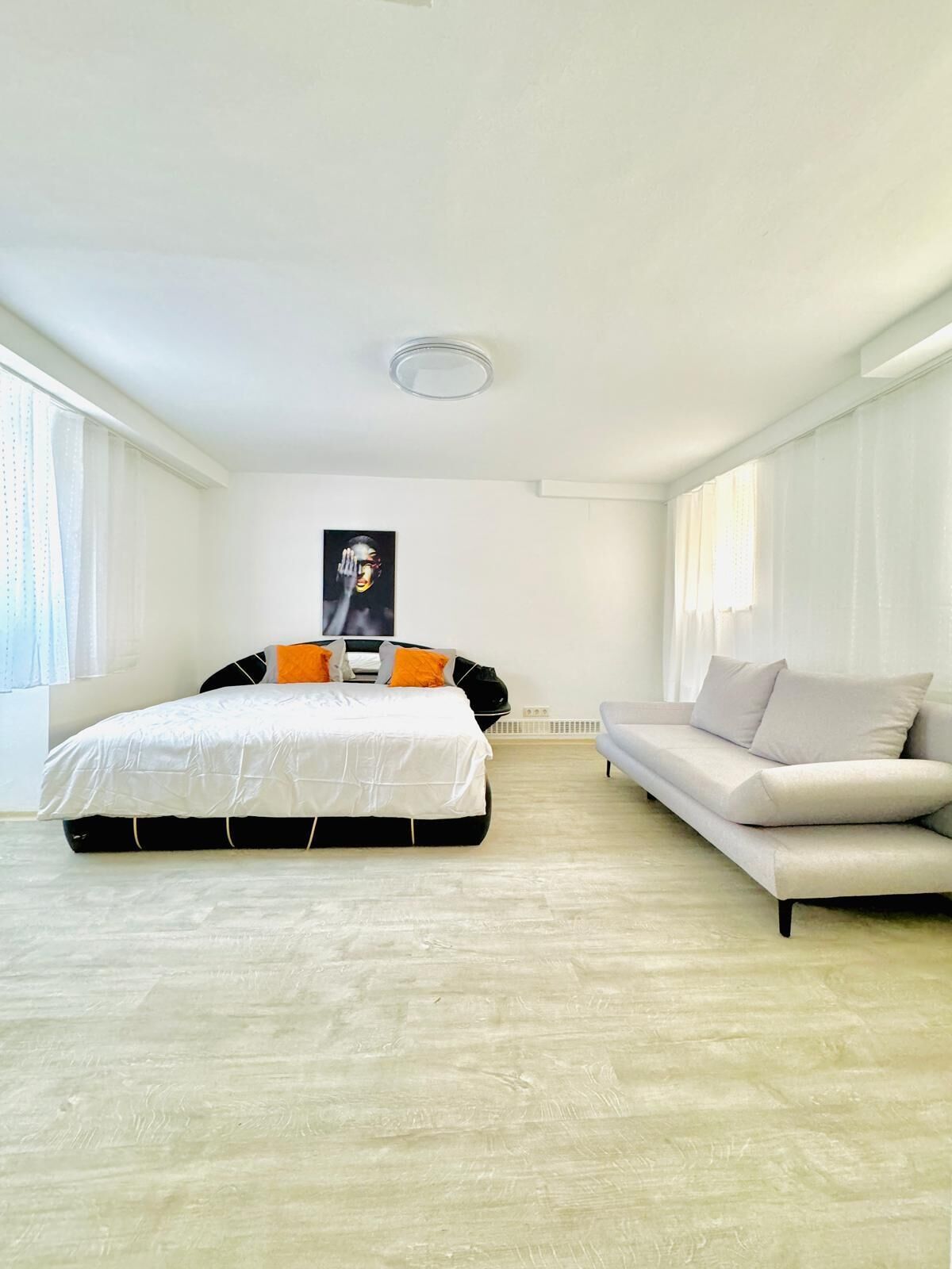 A spacious bedroom with a large bed, a sofa, and a poster on the wall.
