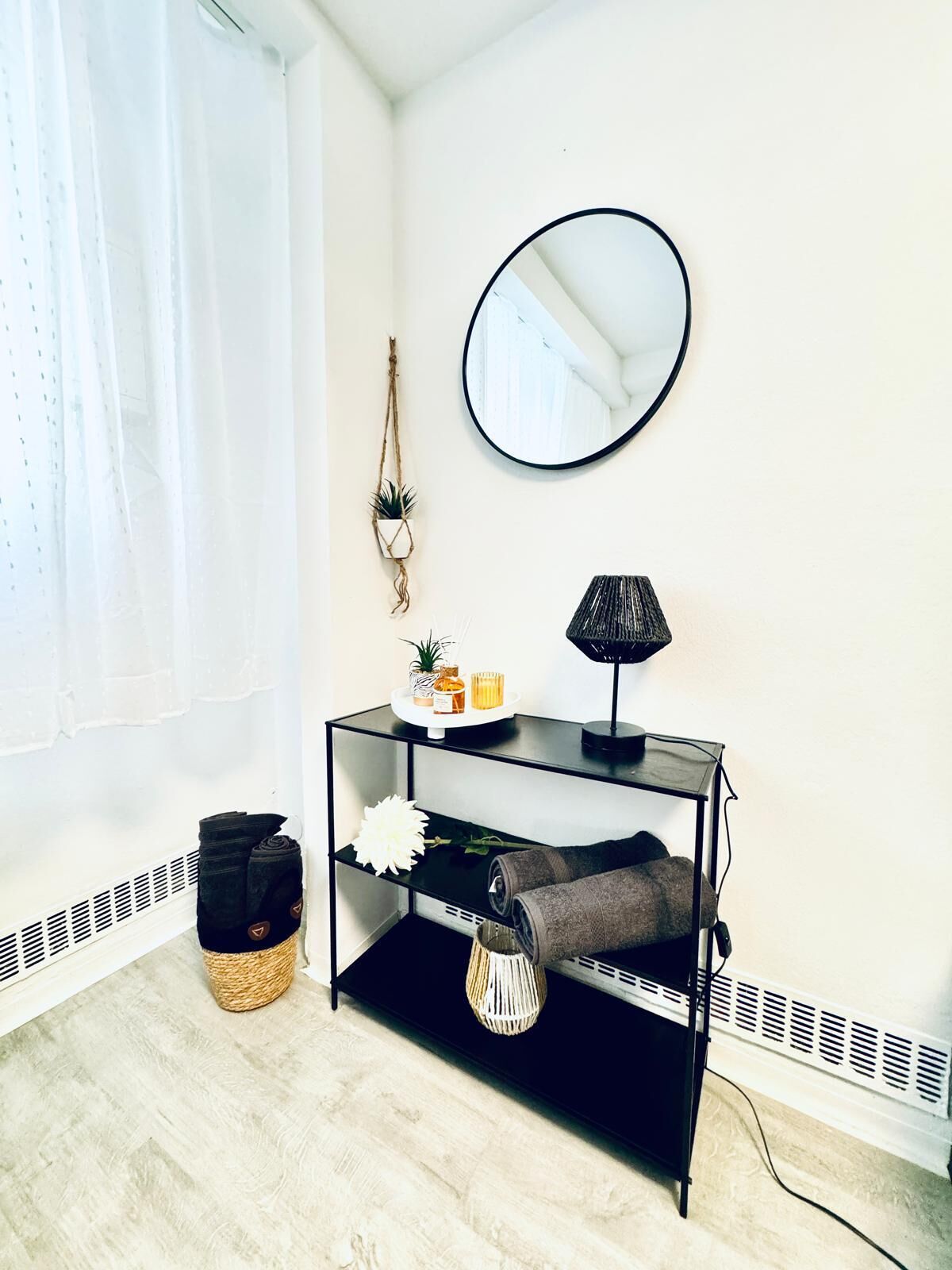 A modern room with a black console table, a round mirror, and a potted plant.