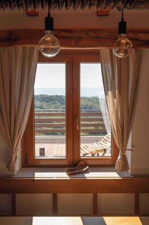 A room with a wooden bench, a window with curtains, and a view of a landscape. - Holiday home with beautiful view (Tržišče)