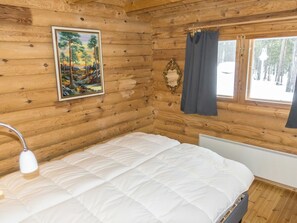 A wooden cabin room with a bed, a painting, a window with curtains, and a radiator. - Kultaranta ii by Interhome (Inari)