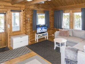 A log cabin interior with a television, sofa, and a small table.