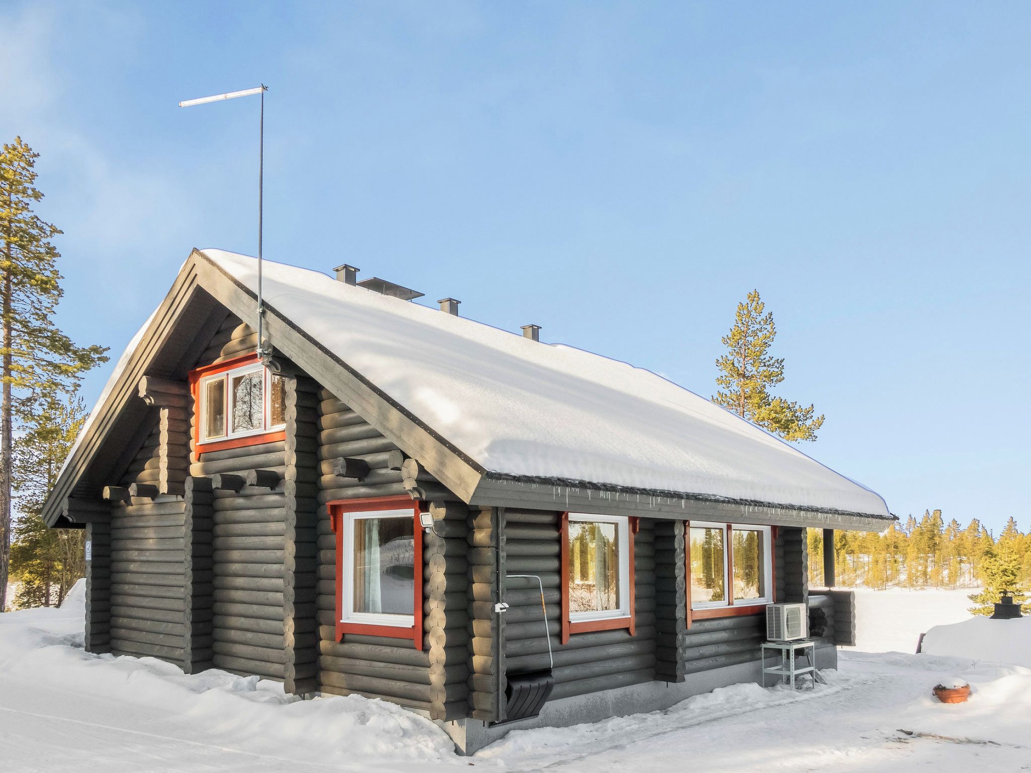 A log cabin with a steep roof, multiple windows, and a chimney.