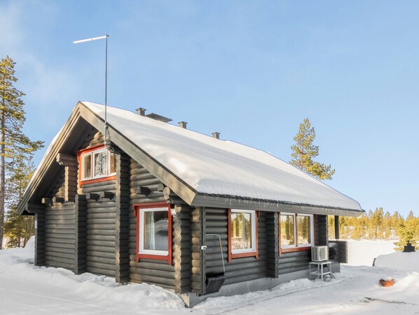 A log cabin with a steep roof, multiple windows, and a chimney.
