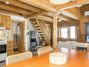 A wooden interior with a kitchen, dining area, and a staircase.