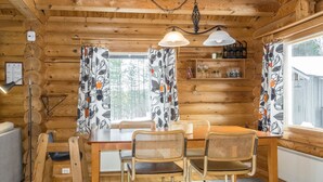 A wooden cabin interior with a dining table, chairs, and a chandelier. - Kultaranta ii by Interhome (Inari)