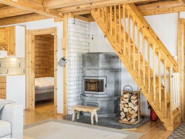 A cozy room with a fireplace, wooden staircase, and a bed.