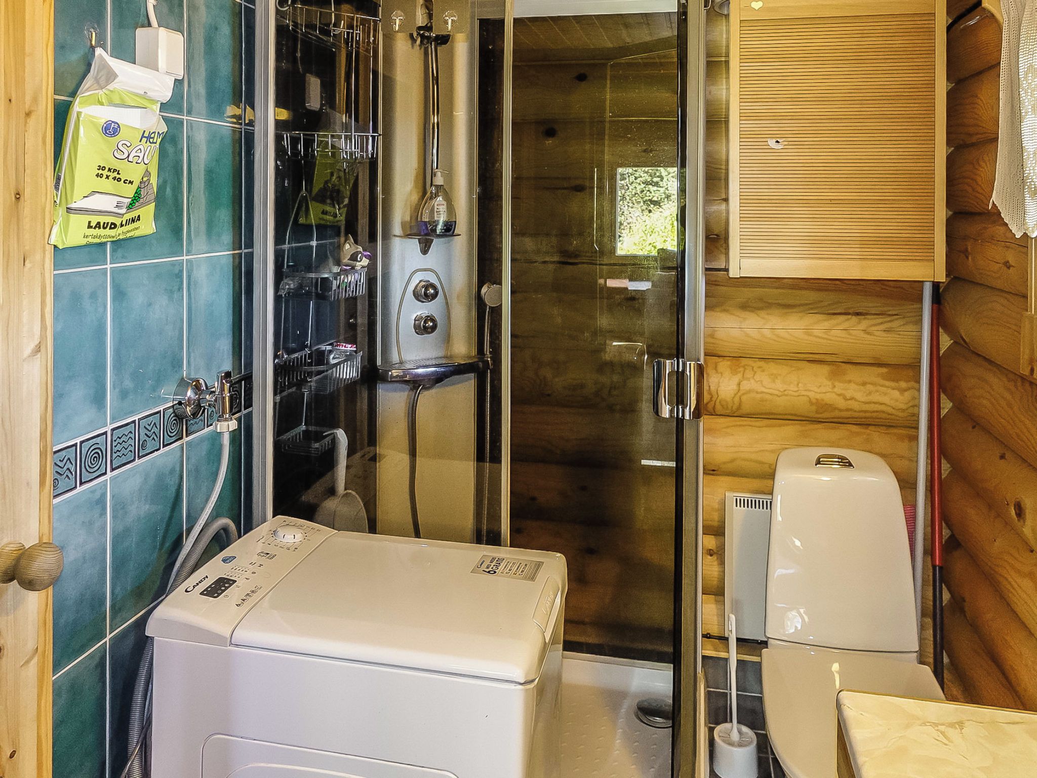 A compact bathroom with a shower enclosure, a toilet, and a washing machine.