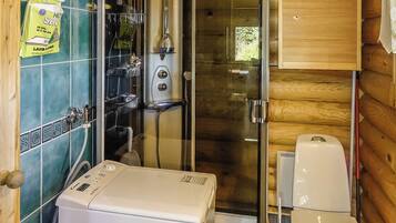 A compact bathroom with a shower enclosure, a toilet, and a washing machine.