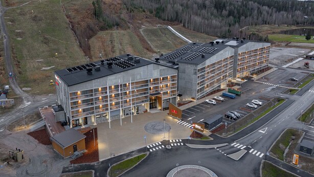 A modern building with multiple floors, large windows, and a parking area. - Break Sokos Hotel Himos (Jamsa)