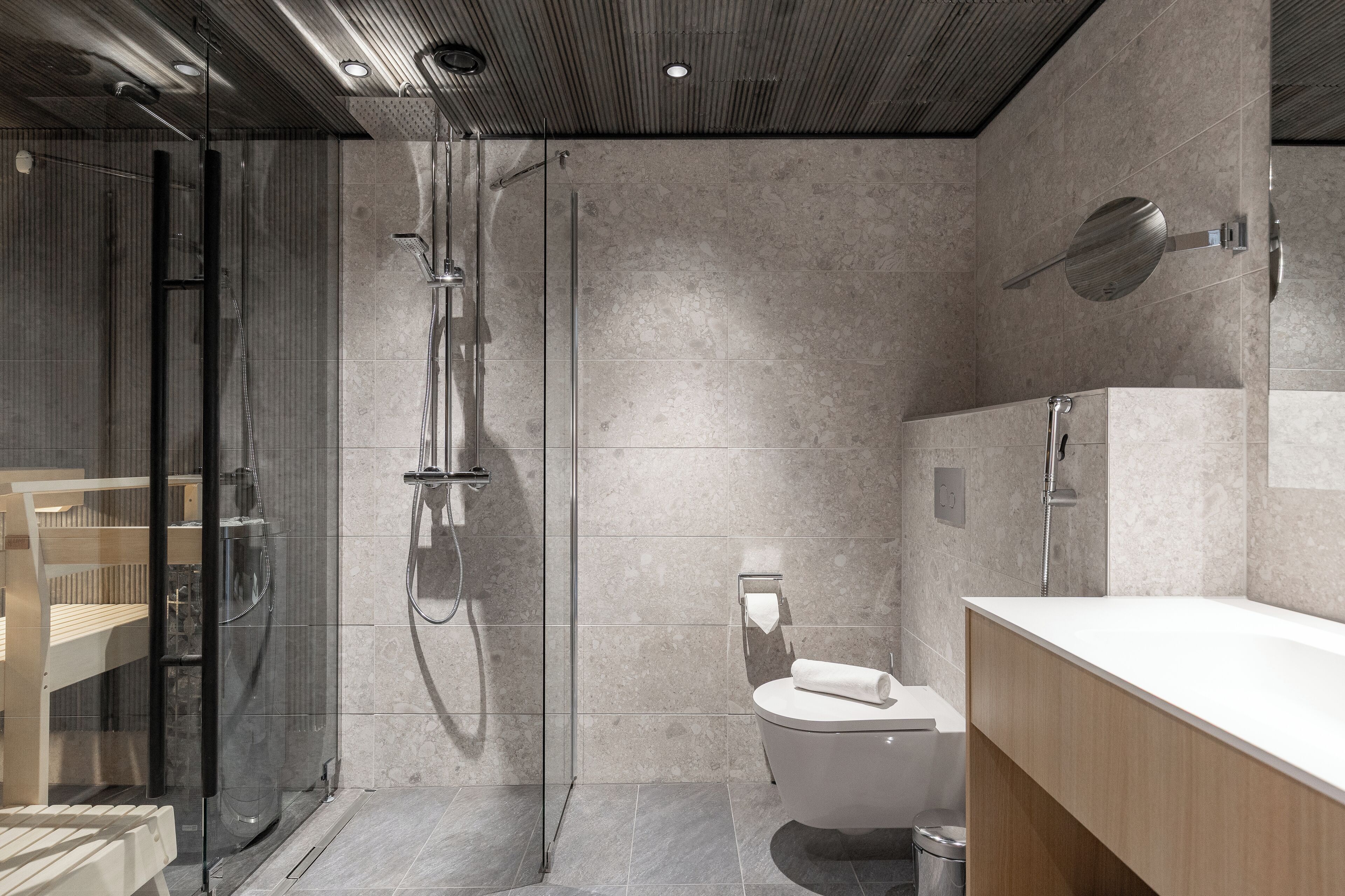 Un baño moderno con cabina de ducha de vidrio, inodoro y tocador de madera.