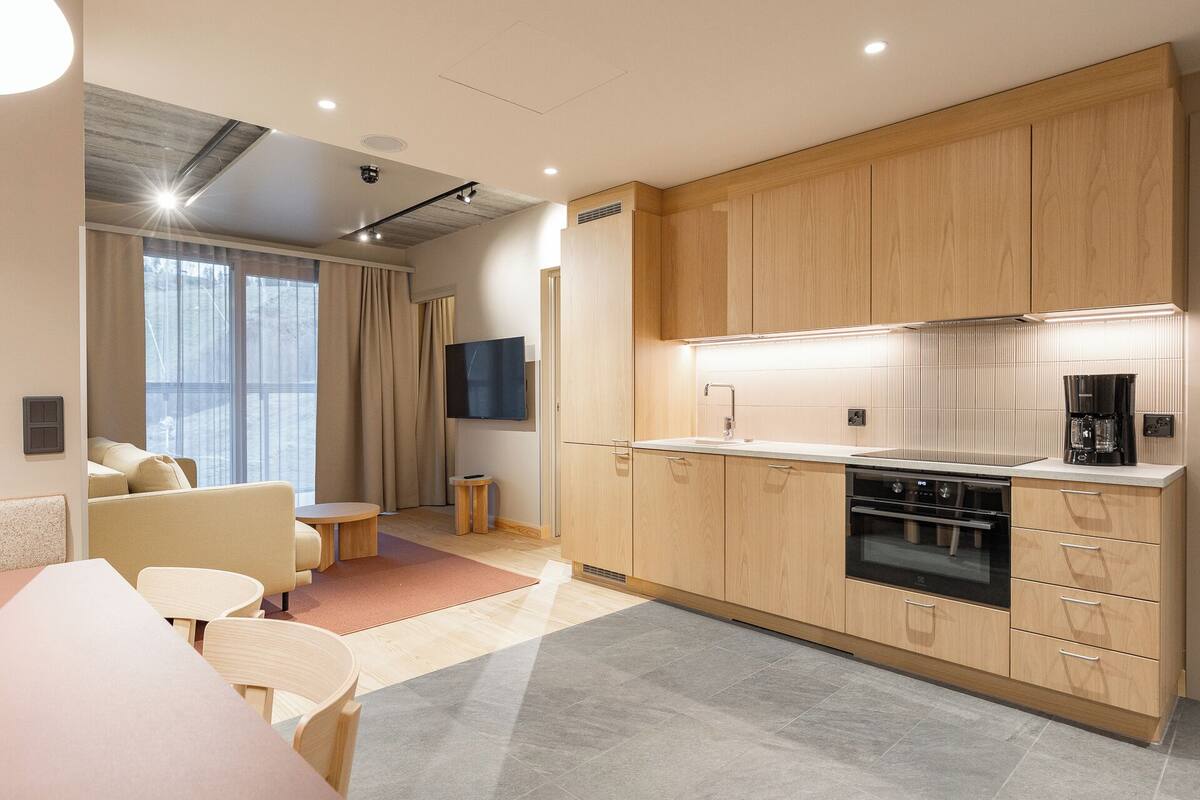 A modern kitchen with wooden cabinets, a built-in oven, and a coffee maker.