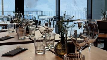 A dining table set with multiple wine glasses, a small potted plant, and a menu.