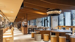 A modern restaurant interior with wooden furniture, large windows, and a central bar area. - Break Sokos Hotel Himos (Jamsa)