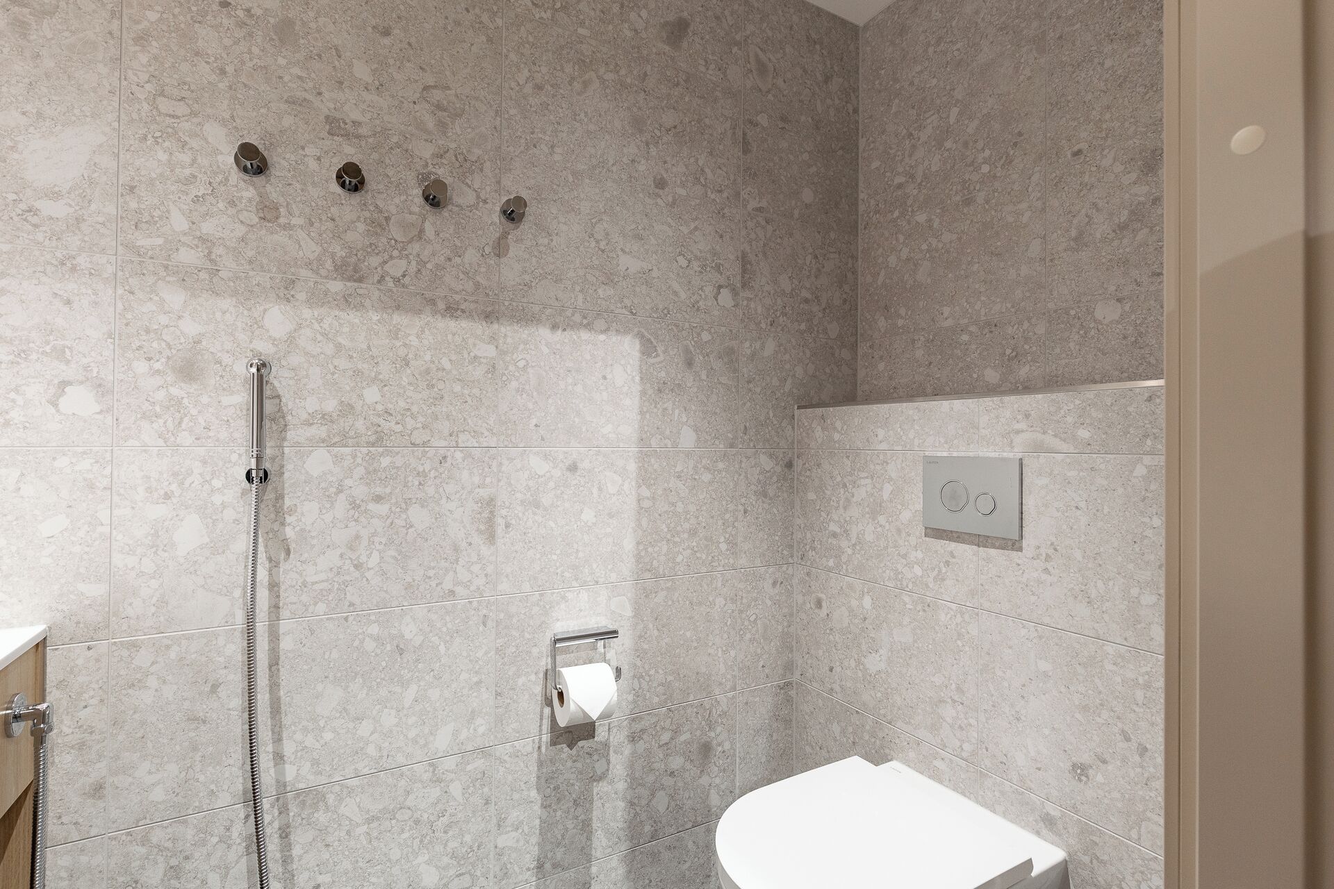 Un baño moderno con ducha, inodoro y perchero.