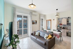 Ein Wohnzimmer mit einer Couch, einem Esstisch und einer Küchenzeile mit gefliestem Fliesenspiegel.