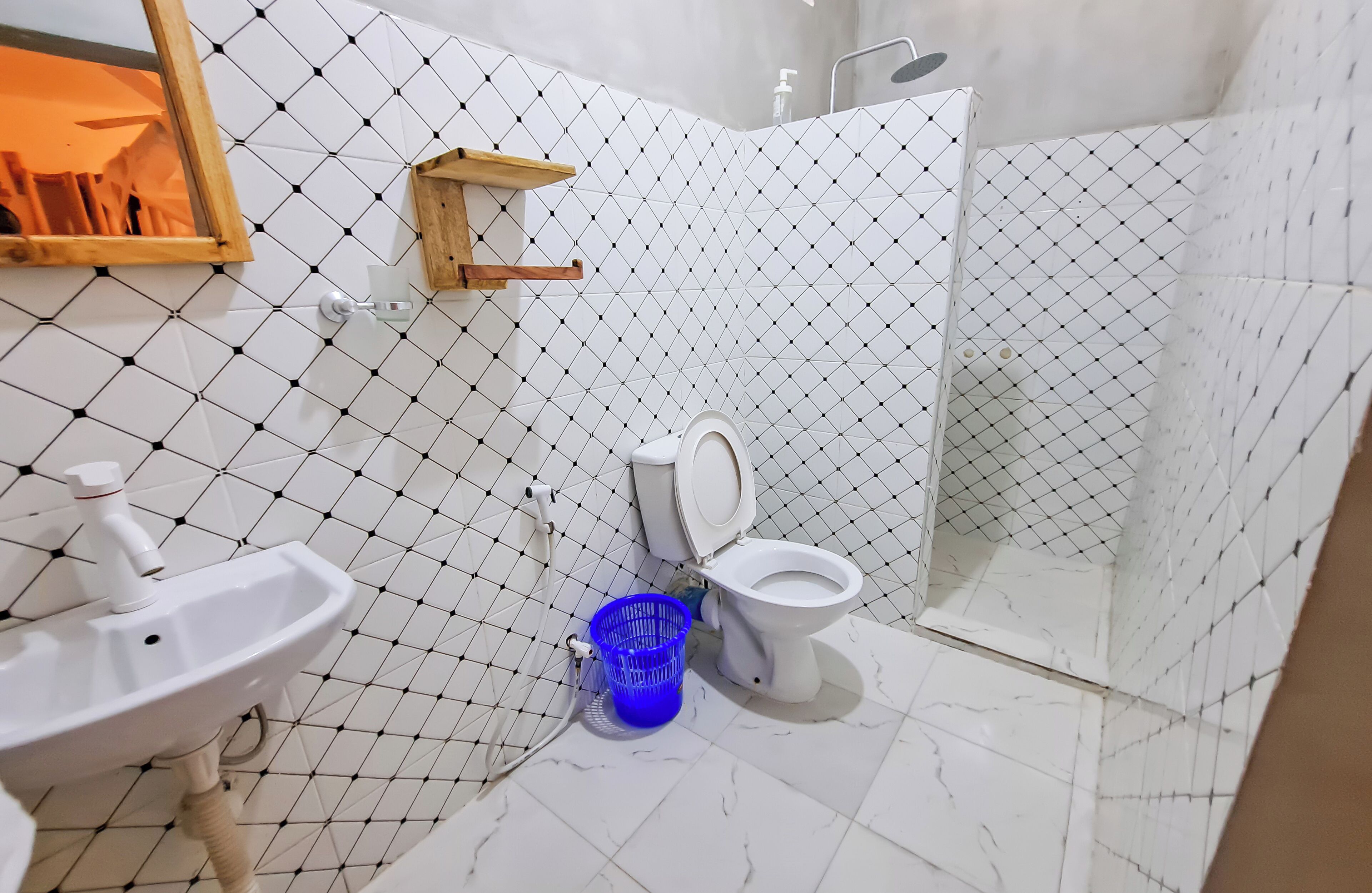 Une salle de bain avec un sol carrelé de carreaux blancs, un lavabo, des toilettes et un espace douche.