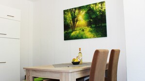 Un comedor con una mesa de madera, dos sillas, una botella y un cuenco de fruta.