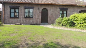 A two-story brick house with a tiled roof, a front door, and two windows with curtains. - Vacation home Bornem, quiet location. Close to Ghent, Antwerp, Mechelen, Puurs (Bornem)