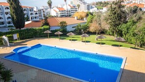 En rektangulær swimmingpool med en klar blå vandoverflade, omgivet af en flisbelagt terrasse.