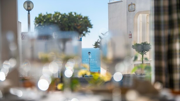 A view through a window with a clear sky, a street lamp, and a sign for 'D. Alma Portuguesa.' - Downtown Apartment - By D`alma Portu (Albufeira)