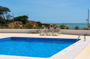 A swimming pool with clear blue water, surrounded by lounge chairs and a lifebuoy. - Apartamento Varandas do Mar (Albufeira)