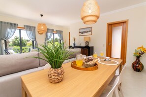 Uma sala de estar moderna com uma mesa de jantar de madeira, um cachepot trançado e um sofá.