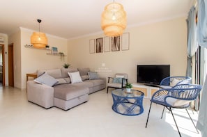 Uma sala de estar moderna com um sofá seccional, uma televisão e cadeiras azuis.
