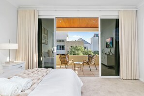 Um quarto espaçoso com uma cama grande, uma varanda com cadeiras de vime e vista para o exterior.