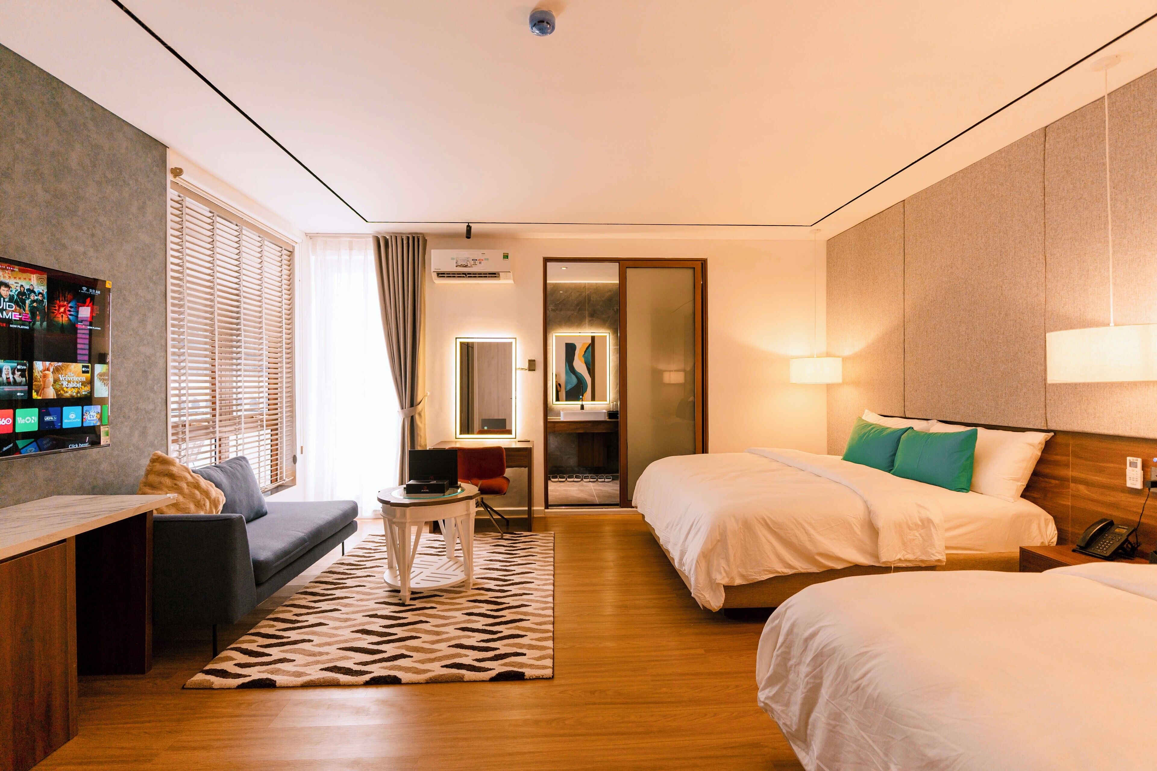A hotel room with two beds, a sofa, a TV, and a small table.