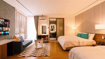 A hotel room with two beds, a sofa, a TV, and a small table.