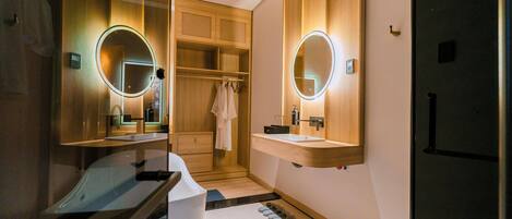Un baño moderno con dos lavabos, armarios de madera e iluminación integrada en el espejo.