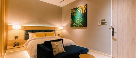 A modern bedroom with a bed, bedside lamps, a sofa, a round table, and a painting on the wall.
