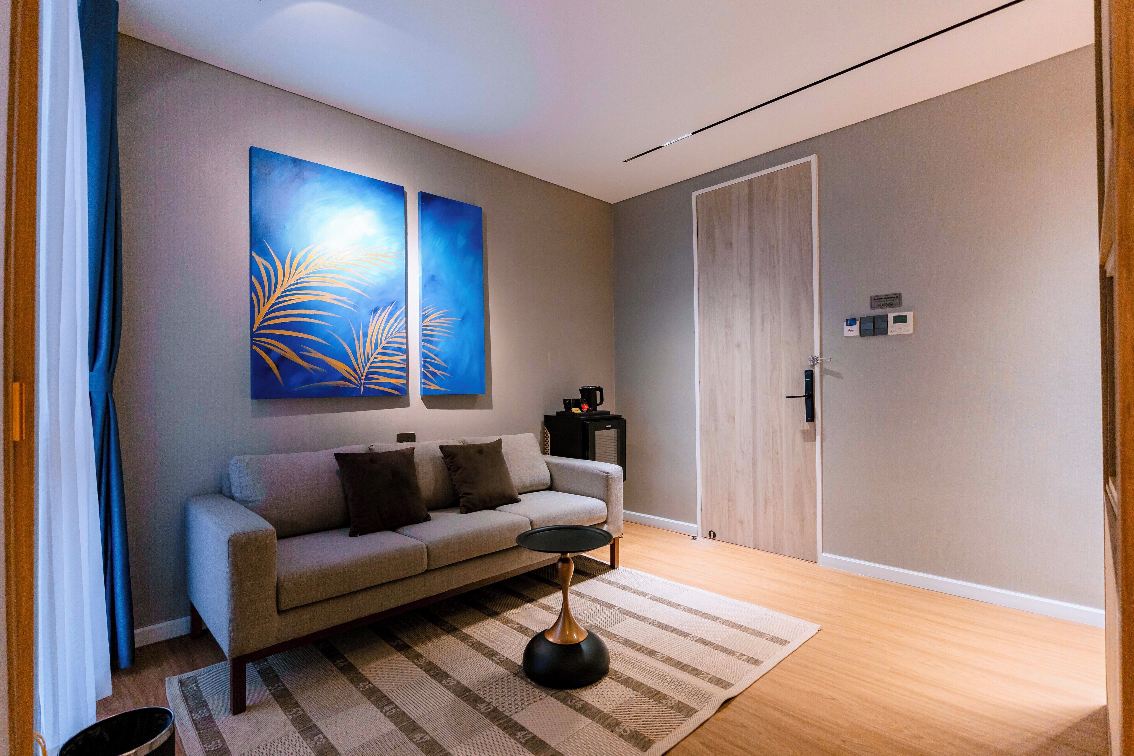 A modern living room with a sofa, a coffee table, and two abstract paintings on the wall.