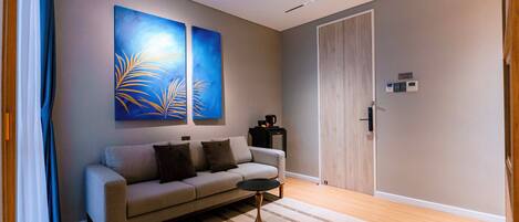 A modern living room with a sofa, a coffee table, and two abstract paintings on the wall.