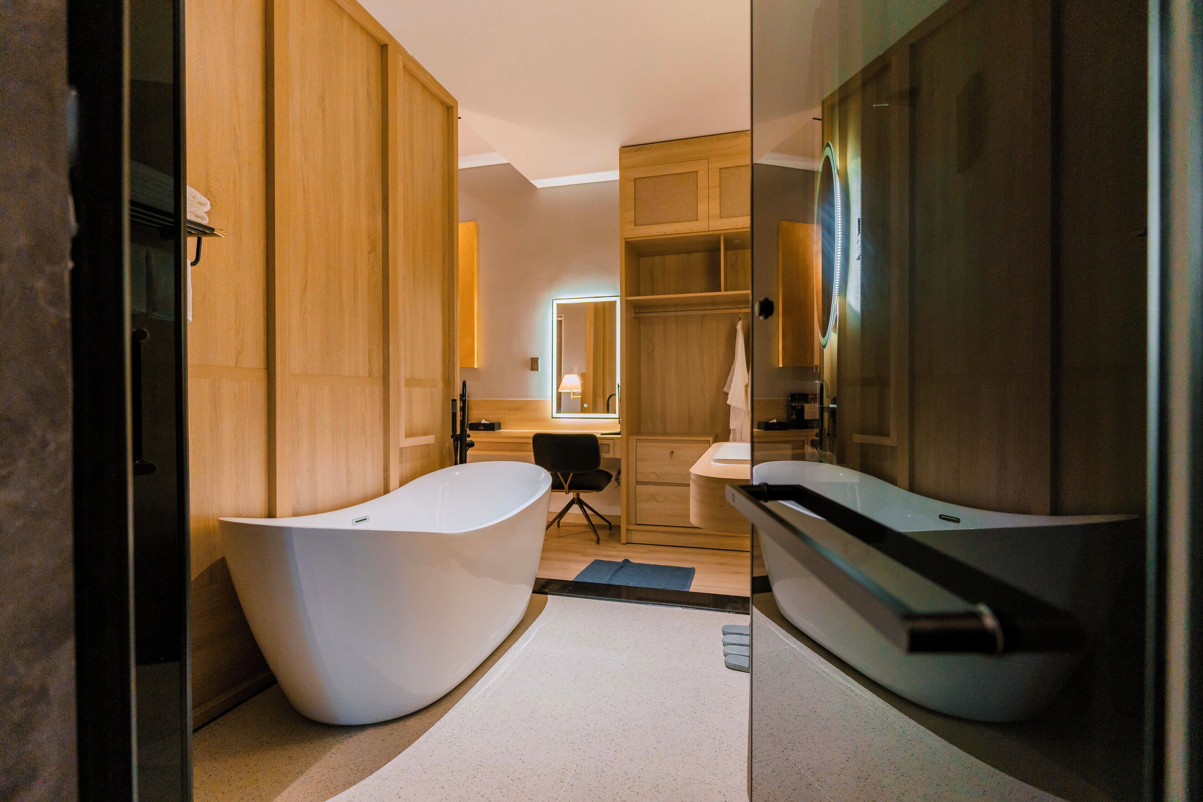 Ein modernes Badezimmer mit zwei freistehenden Badewannen, Holzschränken und einem Spiegel.