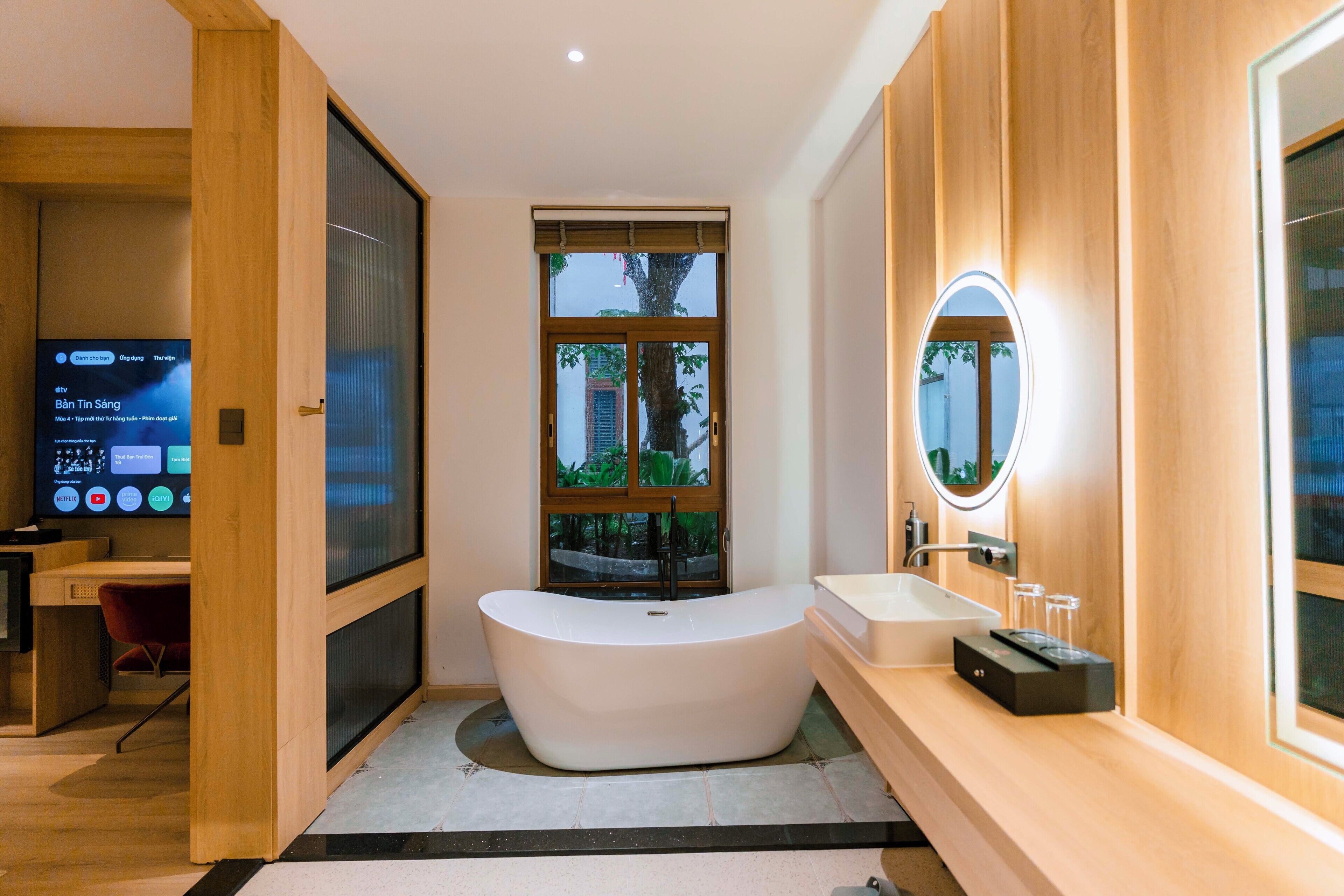 Une salle de bain moderne avec une baignoire sur pieds, un meuble-lavabo avec un miroir et une grande fenêtre.