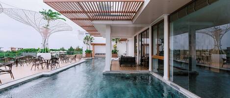 A modern outdoor pool area with seating and a covered patio.