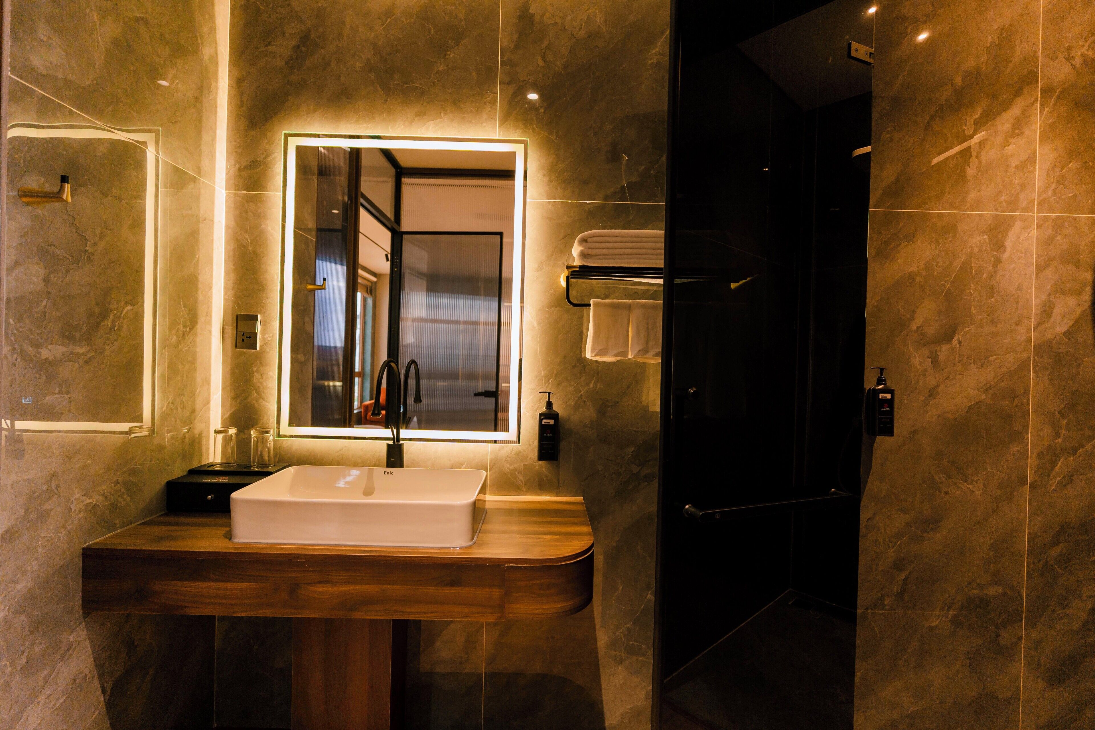Une salle de bain moderne avec un meuble-lavabo en bois, un grand miroir et une cabine de douche en verre.