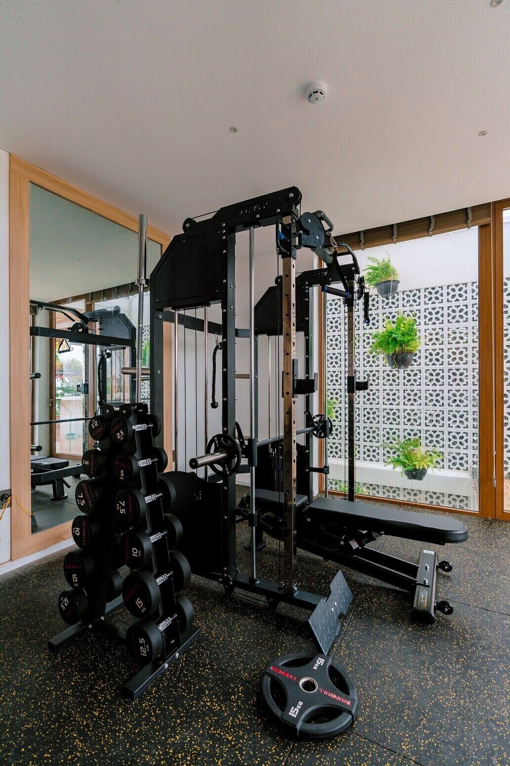 A home gym with a squat rack, weight bench, and a rack of dumbbells.