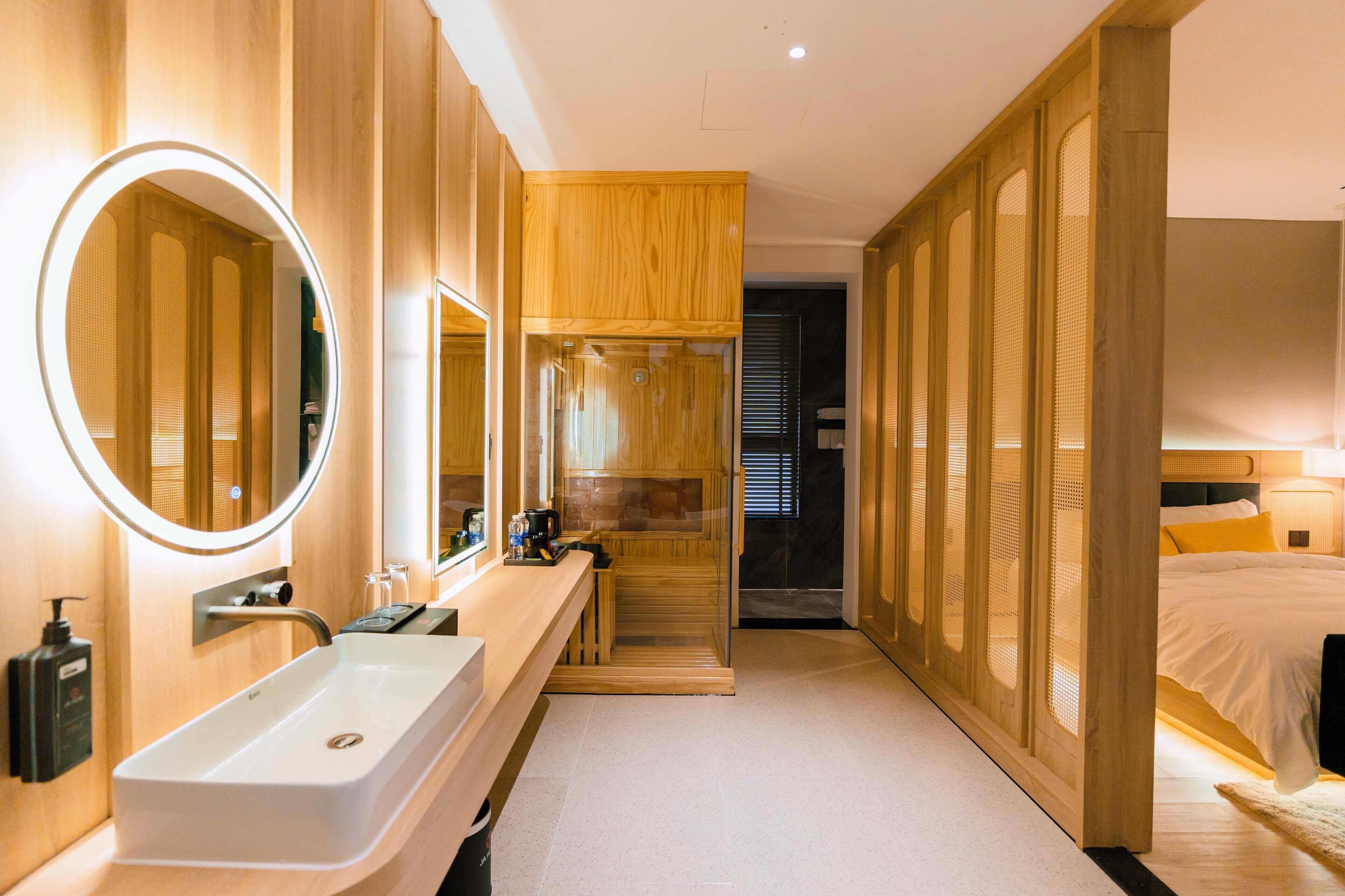 Una habitación de hotel moderna con un amplio tocador de baño, un vestidor y una zona de dormitorio separada.